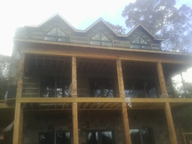 Dormers and porch framing on a large log home under construction — Roof Coating work by our crew in Pierz