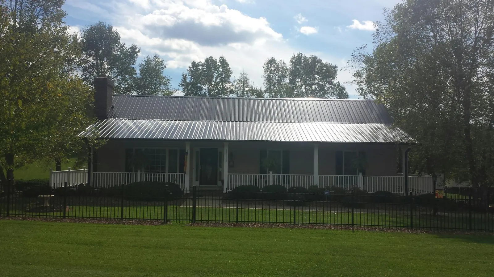 Gray metal roof on a brick ranch with a full width front porch — Gutter Guard Installation work by our crew in Pierz