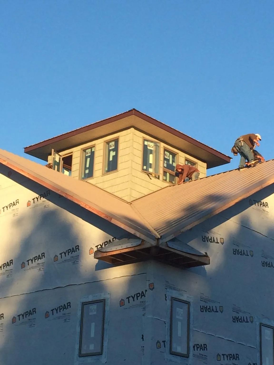 Roofers working around a rooftop cupola on a new metal roof at sunset — Roof Waterproofing in Pierz by Roofing Brothers